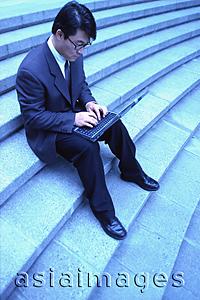 Asia Images Group - Male executive sitting on steps, using laptop