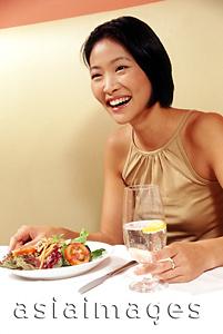 Asia Images Group - Woman holding glass at restaurant, smiling