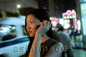 Asia Images Group - Female executive talking on cellular phone with neon in background