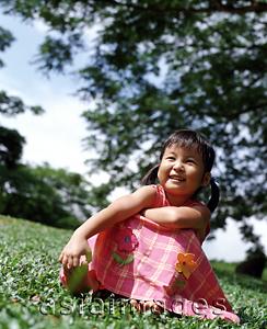 Asia Images Group - Girl sitting on grass, tree in background