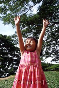 Asia Images Group - Girl stretching arms up, tree in background