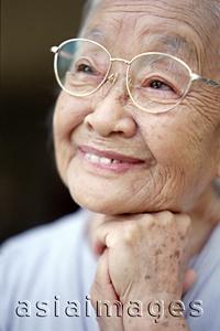 Asia Images Group - Mature woman with glasses, resting chin on fist, smiling