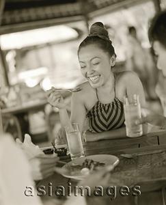 Asia Images Group - Woman eating at restaurant, smiling