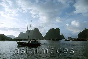 Asia Images Group - Vietnam, Halong Bay, fishing boat under cloudy sky.