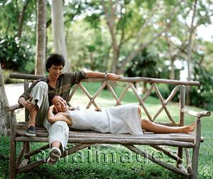 Asia Images Group - Woman lying on bench with head on man's lap, outdoors