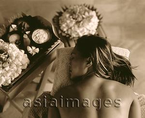 Asia Images Group - Profile of woman lying down with flowers on table next to her