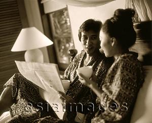 Asia Images Group - Man holding newspaper in bed talking with woman holding cup