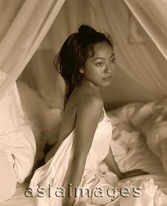 Asia Images Group - Woman draped in sheet sitting in bed