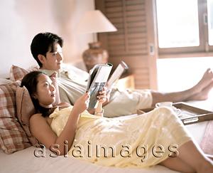 Asia Images Group - Woman and man in bed reading magazines.