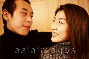 Asia Images Group - Man with arm around woman, looking at each other.