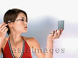Asia Images Group - Profile of woman applying mascara, white background