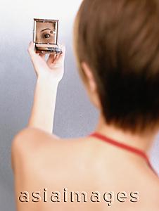 Asia Images Group - Woman looking in compact mirror, rear view