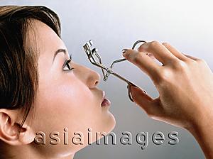 Asia Images Group - Profile of young woman using an eyelash curler