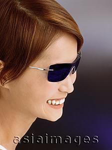 Asia Images Group - Young woman wearing blue tinted sunglasses, smiling