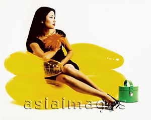 Asia Images Group - Young woman sitting on yellow inflatable chair, green purse