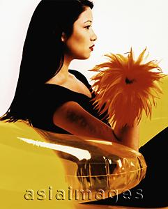 Asia Images Group - Young woman sitting on yellow inflatable chair, profile.