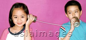 Asia Images Group - Children playing with tin can phone, purple background.