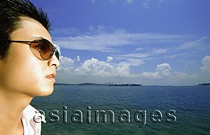 Asia Images Group - Profile of young man with sunglasses, blue sky in background