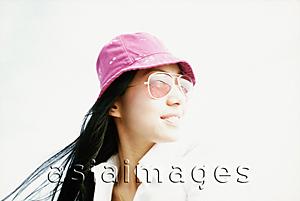 Asia Images Group - Young woman with purple hat and sunglasses looking away, white background