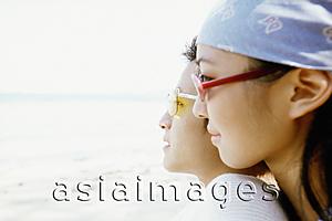 Asia Images Group - Profile of young couple with sunglasses on beach, woman leaning on back of man