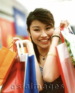 Asia Images Group - Woman holding shopping bags, smiling, portrait.