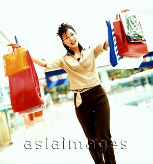 Asia Images Group - Woman holding shopping bags, smiling.