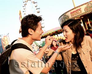 Asia Images Group - Man feeding fishballs to woman at carnival.