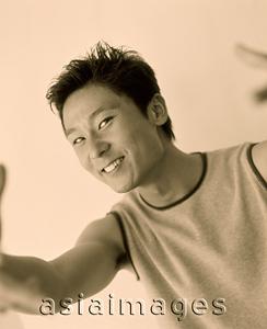 Asia Images Group - Young man smiling and gesturing to camera.