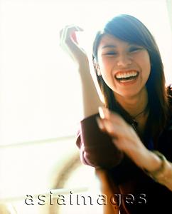 Asia Images Group - Young woman gesturing and laughing, portrait.