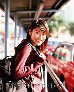 Asia Images Group - Young woman with backpack at taxi stand, portrait.