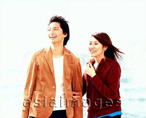 Asia Images Group - Young couple laughing, city skyline behind.