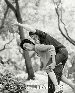 Asia Images Group - Young man piggybacking woman on nature path.