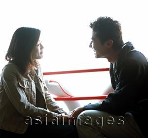 Asia Images Group - Young adult couple sitting by rails talking.