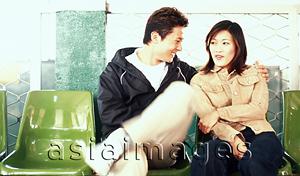 Asia Images Group - Young adult couple sitting on plastic chairs.