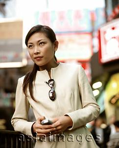Asia Images Group - Woman holding cellular phone in busy street.