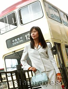 Asia Images Group - Executive woman standing, bus in background.