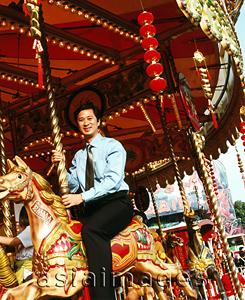Asia Images Group - Male executive sitting on carousel.
