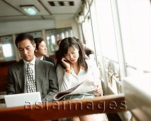 Asia Images Group - Male executive using laptop, female using cellular phone, outdoors.