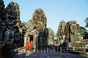 Asia Images Group - Cambodia, Angkor Thom, monks walking between face towers of the Bayon