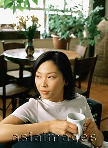 Asia Images Group - Woman sitting with a cup looking off camera