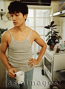 Asia Images Group - Man holding cup, kitchen in background