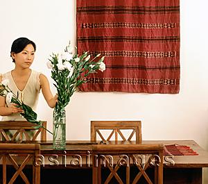 Asia Images Group - Woman arranging flowers in dining room