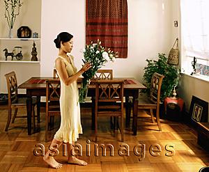 Asia Images Group - Woman holding flowers, walking in dining room