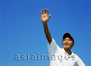 Asia Images Group - Mature man with red cap, waving, blue sky