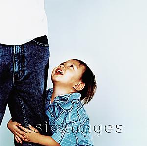 Asia Images Group - Young boy grabbing leg, looking up