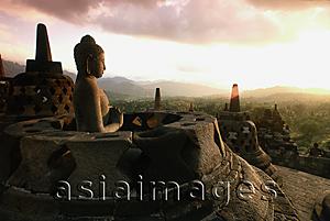 Asia Images Group - Indonesia, Java, Buddha figure at Borobudur temple at dawn,  mountains in background