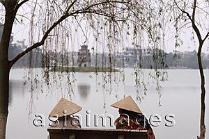 Asia Images Group - Vietnam, Hanoi, Two women sit on a bench overlooking Huan Kiem Lake.