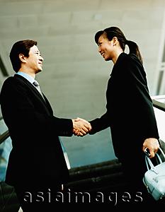 Asia Images Group - Executive pair shaking hands on escalator.