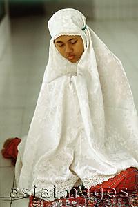 Asia Images Group - Indonesia, student clutches her Koran beneath a prayer shawl.