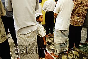 Asia Images Group - Singapore, boy wearing songkok prayer cap stands among men worshipping at the Hajjah Fatimah Mosque.